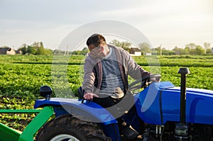 A farmer on a tractor monitors the operation of equipment for harvesting potatoes. Farming and farmland. Simplify speed up work