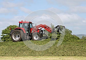 Farmer on tractor packing down silage stack