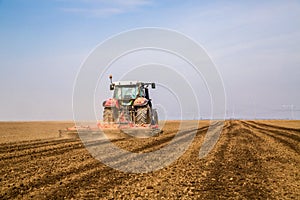 Farmer in tractor preparing land with seedbed cultivator.