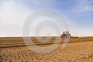 Farmer in tractor preparing land with seedbed cultivator.