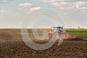 Farmer in tractor preparing land with seedbed cultivator.