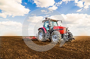 Farmer in tractor preparing land with seedbed cultivator.