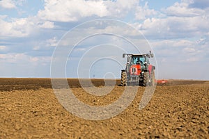 Farmer in tractor preparing land with seedbed cultivator.