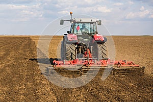 Farmer in tractor preparing land with seedbed cultivator.