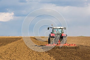 Farmer in tractor preparing land with seedbed cultivator.