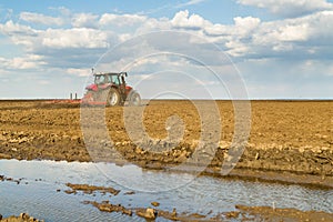 Farmer in tractor preparing land with seedbed cultivator.