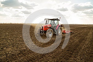 Farmer in tractor preparing land with seedbed cultivator.