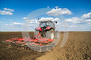 Farmer in tractor preparing land with seedbed cultivator.