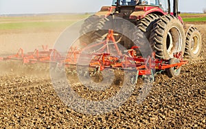 Farmer in tractor preparing land with seedbed cultivator photo