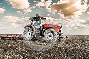 Farmer in tractor preparing land with seedbed cultivator.