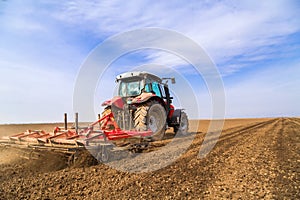 Farmer in tractor preparing land with seedbed cultivator.