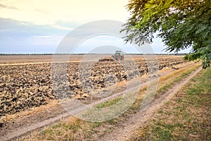 Farmer in tractor preparing land with seedbed cultivator as part of pre seeding activities of agricultural works at farmlands