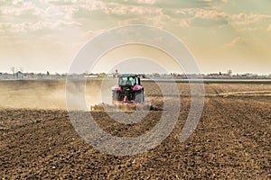 Farmer in tractor preparing land with seedbed cultivator as part of pre seeding activities in early spring season of agricultural