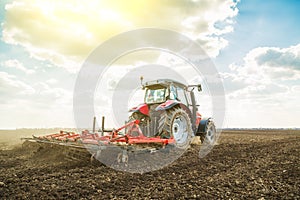 Farmer in tractor preparing land with seedbed cultivator. photo