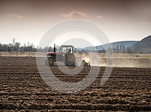 Farmer in tractor preparing land with seedbed cultivator in early spring