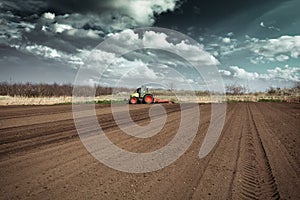 Farmer in tractor preparing land with seedbed cultivator in early spring