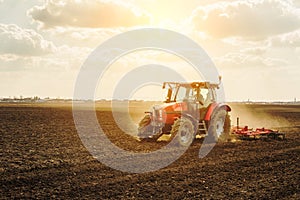 Farmer in tractor preparing land with seedbed cultivator. photo