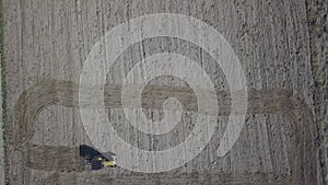 A farmer on a tractor with a seeder sows grain in plowed land in a private field in the village area. Mechanization of spring fiel