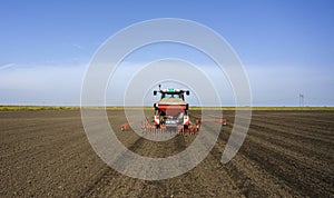 Farmer with tractor seeding crops at field