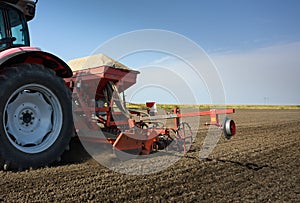 Farmer with tractor seeding crops at field