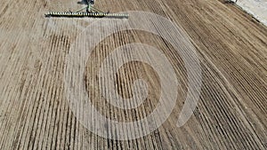 Farmer on tractor with seeding machinery driving over field sows seeds or grain of wheat or corn. Agricultural