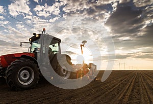 Farmer with tractor seeding - sowing crops at agricultural field