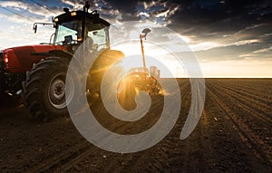 Farmer with tractor seeding - sowing crops at agricultural field