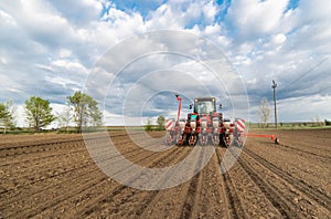 Farmer with tractor seeding - sowing crops at agricultural field