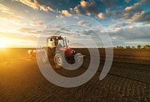 Farmer with tractor seeding - sowing crops at agricultural field