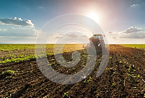 Farmer with tractor seeding - sowing crops at agricultural field