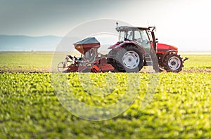 Farmer with tractor seeding - sowing crops at agricultural field