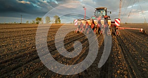 Farmer with tractor seeding - sowing crops at agricultural field