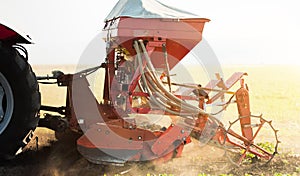 Farmer with tractor seeding - sowing crops at agricultural field