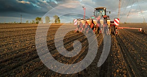 Farmer with tractor seeding - sowing crops at agricultural field photo