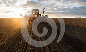 Farmer with tractor seeding - sowing crops at agricultural field