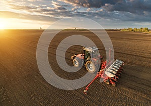 Farmer with tractor seeding - sowing crops at agricultural field photo