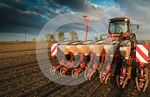 Farmer with tractor seeding - sowing crops at agricultural field photo