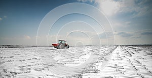 Farmer with tractor seeding - sowing crops at agricultural fields in winter