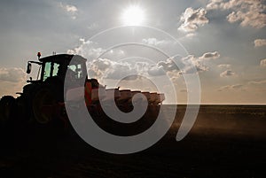 Farmer with tractor seeding in sunset photo