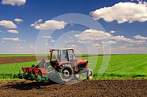 Farmer with tractor sowing on agricultural fields in spring