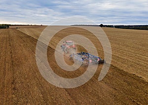 Farmer with tractor on wide field tilling the soil