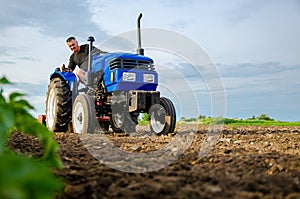 A farmer on a tractor works the field. Milling soil, crushing and loosening ground before cutting rows. Land cultivation. Farming
