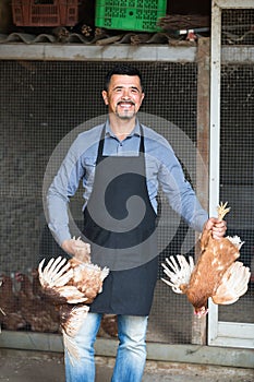 Farmer with two chickens in hands on farm