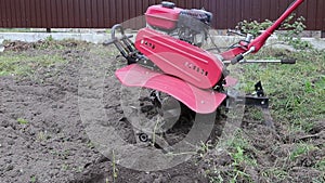 a farmer uses a red-colored technique to cultivate a small plot of land. plows, cultivates the land