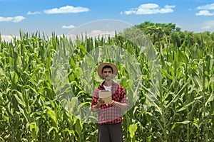 Farmer using digital tablet computer in cultivated corn field plantation
