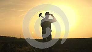 A farmer walks through the field with a shovel in rubber boots to dig the soil of the land at sunset, agriculture, land