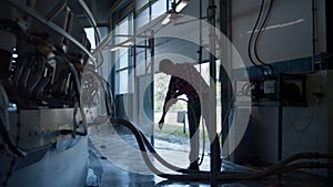 Farmer washing milking system in technological farm using hose. Dairy technology