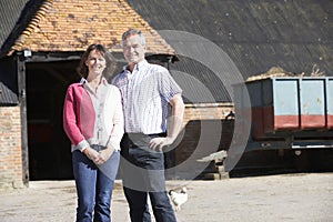 Farmer And Wife Standing In Front Of Farm Building