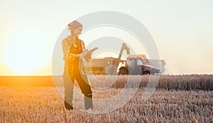 Farmer woman and combine harvester on wheat field