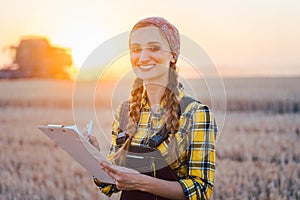 Farmer woman and combine harvester on wheat field